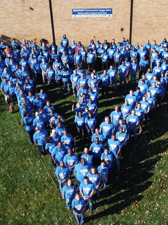 Gruppe von BENTELER Mitarbeitern im aufgestellt im BENTELER Logo