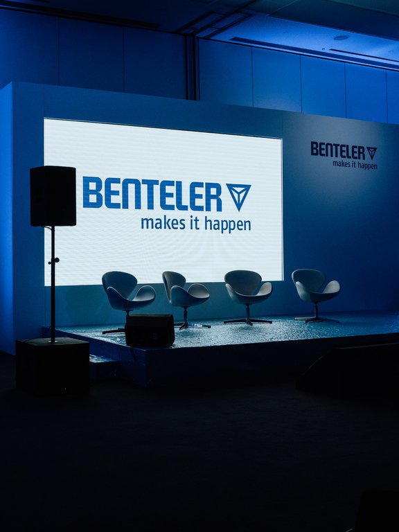 A presentation room with a screen displaying the BENTELER logo and chairs